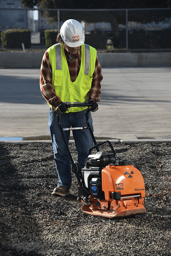 Worker operating battery plate compactor